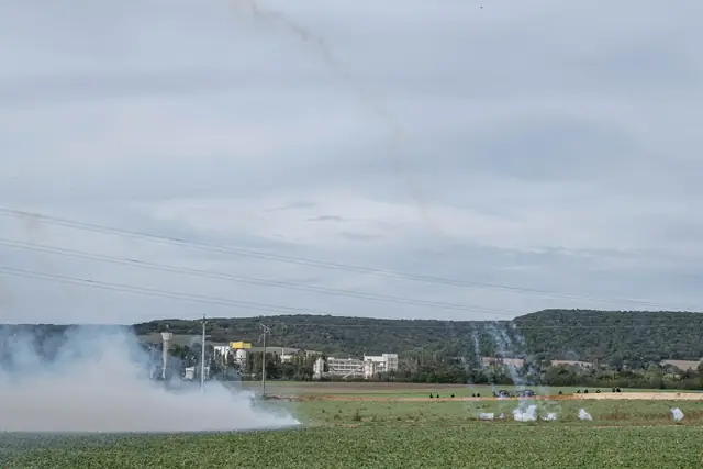 Clouds of tear gas rise above the field facing the factory
