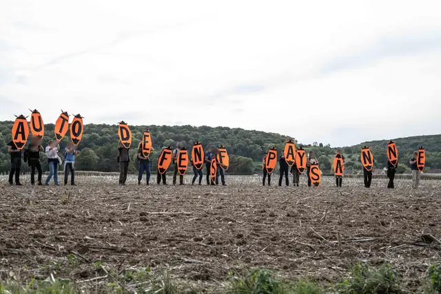 In a ploughed field, orange letters spell out “Farmers’ self-defence” (“Autodéfense paysanne”)