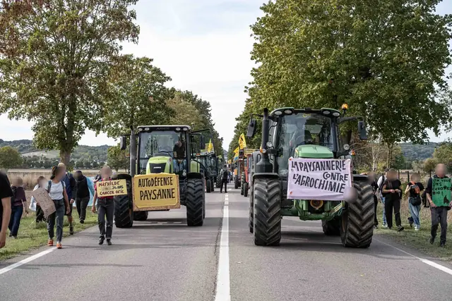 Tractors bearing the signs “Farmers’ self-defence” (“Autodéfense paysanne”) and “The peasantry against agrochemistry” (“La paysannerie contre l’agrochimie”) advance between the plane trees