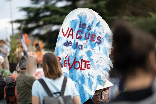 A large wave painted in blue, “The Waves of Revolt” (“Les Vagues de la révolte”), carried in the march